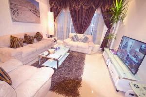 ein Wohnzimmer mit 2 Sofas und einem TV in der Unterkunft Hotel Leaders Plaza Mahboula in Kuwait