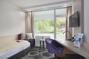 una camera d'albergo con letto, scrivania e finestra di Trip Inn Landhotel Badsoden-Salmünster a Bad Soden-Salmünster