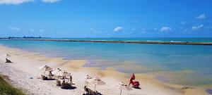 een strand met parasols en de oceaan bij Condomínio Enseada dos Corais apto completo in Cabo de Santo Agostinho