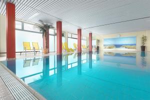 une grande piscine avec des chaises jaunes dans un bâtiment dans l'établissement Trip Inn Landhotel Badsoden-Salmünster, à Bad Soden-Salmünster