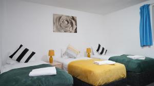 um quarto com duas camas com lençóis verdes e amarelos em E2M Stays 3Bed Spacious House Free Parking Close To Heathrow em Farnham Royal