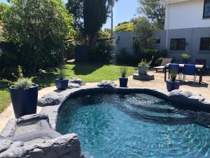 una piscina en un patio con una frontera rocosa en Pelican Lodge Guesthouse, en Sedgefield