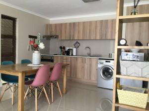 a kitchen with a wooden table and pink chairs at Appartamento Azure 23 - Big Bay in Big Bay