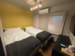 a bedroom with two beds and a desk and a window at Guest House Numazu Port - Vacation STAY 18050v in Numazu