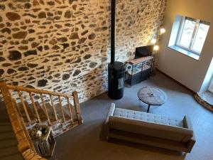 een woonkamer met een bank en een stenen muur bij La clé des champs de Laumont in Saint-Diéry