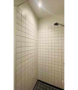 W łazience z bielonymi ścianami wyłożonymi kafelkami znajduje się prysznic. w obiekcie ApartmentInCopenhagen Apartment 1565 w Kopenhadze