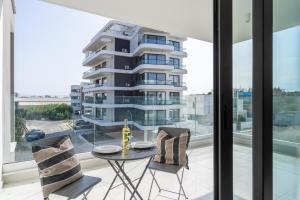 拉納卡的住宿－Taupe’s 2-Bedroom Apartment in Larnaca，一个带桌椅的阳台和一座高高的建筑
