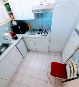 uma pequena cozinha com electrodomésticos brancos e uma cadeira vermelha em La Victoire em Fréjus