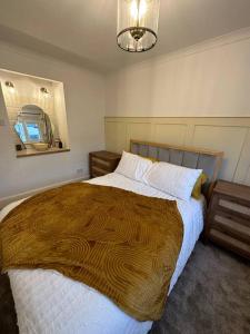 a bedroom with a large bed and a chandelier at Lavender Cottage with a hot tub in Deganwy