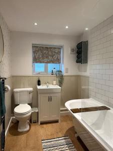 a bathroom with a toilet and a sink and a tub at Lavender Cottage with a hot tub in Deganwy