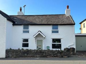a white house with a stone wall at Lavender Cottage with a hot tub in Deganwy