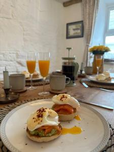 a plate with two egg sandwiches on a table with drinks at Lavender Cottage with a hot tub in Deganwy