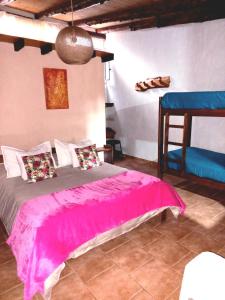 um quarto com uma cama com um cobertor rosa em Cabañas Los Nonos em El Bolsón