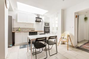 a kitchen with white cabinets and a table and chairs at Grande maison 12Personnes 4CH-2SDB - Êxterieur -proche Lille in Roubaix