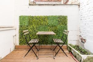 stół i dwa krzesła przed zieloną ścianą w obiekcie Grande maison 12Personnes 4CH-2SDB - Êxterieur -proche Lille w mieście Roubaix