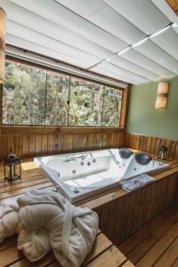 uma grande casa de banho com banheira e uma grande janela em Pousada Canto da Nascente em Monte Verde