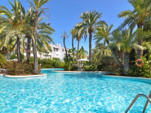 a swimming pool with palm trees in a resort at Luxurious Beachside in the Heart of Puente Romano in Marbella
