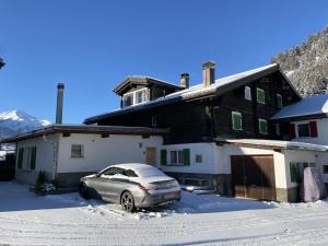 a car parked in front of a house in the snow at Ferienhaus Casa Pistur in Disentis