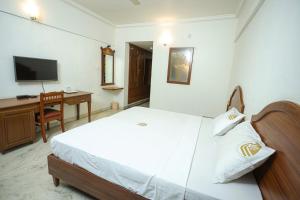 a bedroom with a bed and a desk and a television at Liwa Tower Hotel & Business Center in Kunnamkulam