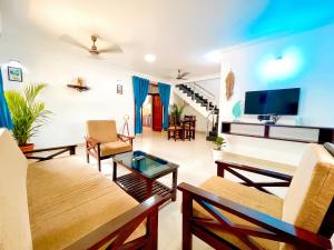 a living room filled with furniture and a flat screen tv at Calvin's 3 BDR Villa in Benaulim