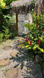 um jardim com telhado de palha e algumas flores em Recanto da Floresta Suites em Ubatuba
