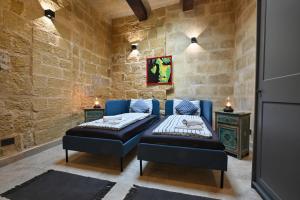 a bedroom with two beds in a stone wall at Il Luzzu - more room for you! in Victoria