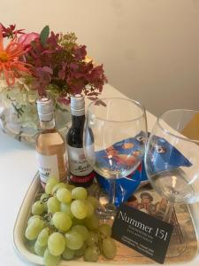 een dienblad met druiven en wijnglazen op een tafel bij Nummer 151 villastudios in Hasselt