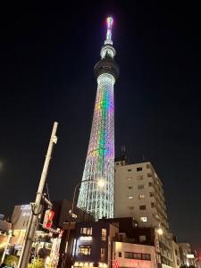 een hoge toren verlicht in regenboogkleuren 's nachts bij ワイズパーク向島 in Tokyo
