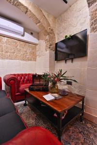 a living room with a couch and a tv on a wall at Il Luzzu - more room for you! in Victoria