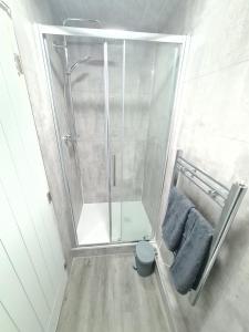 łazienka z prysznicem i 2 niebieskimi ręcznikami w obiekcie Homestay by BIC Legends 2 w mieście Batley Carr