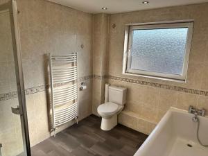 a bathroom with a toilet and a window and a tub at Spacious 3 bed house in Wombwell in Wombwell