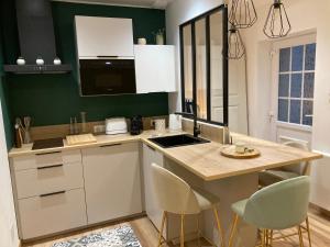 a kitchen with white cabinets and a counter with chairs at LE SAINT CYP - Toulouse - appart entier cosy et au calme, proche du métro in Toulouse