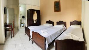 a bedroom with two beds with white sheets at Hotel América in Recife