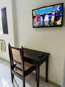 uma televisão numa parede com uma mesa de madeira e uma cadeira em Hotel América no Recife