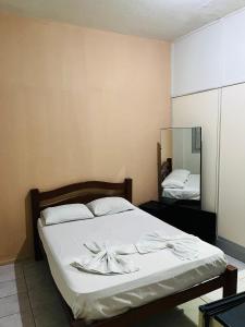 um quarto com uma cama com lençóis brancos e um espelho em Hotel América no Recife