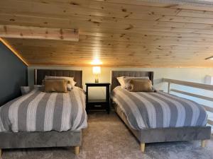 two beds in a bedroom with a wooden ceiling at Froggy Goggle Barn in Marathon