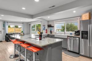 une cuisine équipée d'appareils électroménagers en acier inoxydable et de tabourets de bar orange dans l'établissement Lake Cruiser Cottage, à Manson