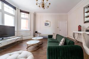 a living room with a green couch and a tv at Spacious 1 BDR apt - 2min to Bond Str Station in London