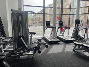 a gym with several tread machines and a large window at Charming 2-Bed Apartment in Salford newly built in Manchester