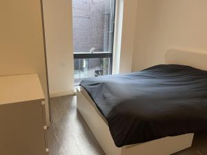 a bedroom with a black bed and a window at Charming 2-Bed Apartment in Salford newly built in Manchester