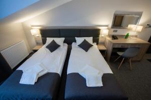 duas camas num quarto de hotel com uma secretária e uma cadeira em Jurajski Kryształ em Zaborze