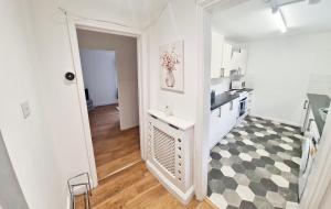 a white kitchen with a black and white checkered floor at 2 Bed Spacious Apartment, Sleeps 4, Free Wifi, Free Parking, Amenities Nearby, Good Transport Links Nearby, Contractors and Holidays in Harlow +6 photos