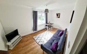 a living room with a blue couch and a television at 2 Bed Spacious Apartment, Sleeps 4, Free Wifi, Free Parking, Amenities Nearby, Good Transport Links Nearby, Contractors and Holidays in Harlow
