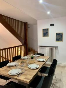 a wooden table with chairs and plates and wine glasses at Maison Okaina, Sauna, Au centre-ville de Macon in Mâcon