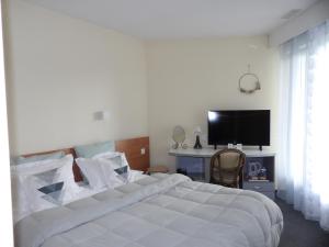 a bedroom with a large white bed and a television at Logis Hotel Restaurant Le Jardin Délice in Saint-Victor