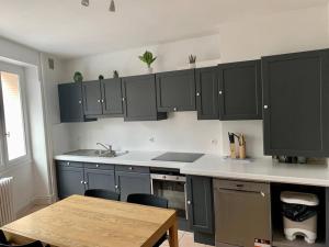 a kitchen with black cabinets and a wooden table at Maison Okaina, Sauna, Au centre-ville de Macon in Mâcon +17 photos