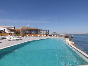 a large swimming pool next to a body of water at 818 Centro Náutico Bungalows in Vila Real de Santo António