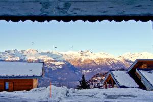 una montaña cubierta de nieve con edificios y techos nevados en Réveil féerique au cœur des alpes - Vercorin en Vercorin