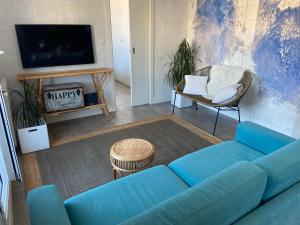 un salon avec un canapé bleu et une télévision dans l'établissement BrisasVTsansebastian In Zurriola Beach, Penthouse, sea views, à Saint-Sébastien