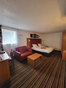 um quarto de hotel com uma cama, um sofá e uma cadeira em Kyriad Saint Quentin en Yvelines - Montigny em Montigny-le-Bretonneux